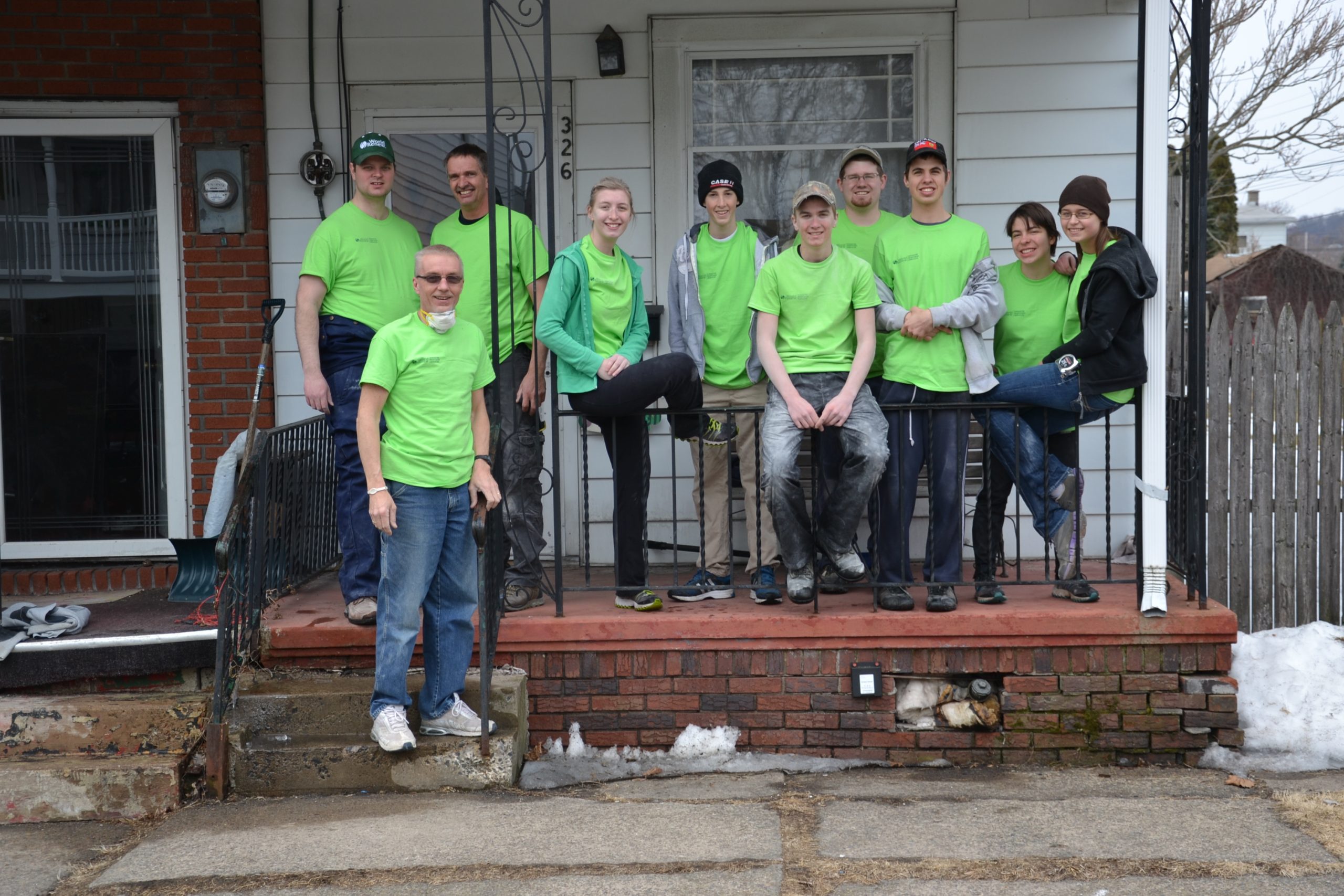 A group of volunteers in green T-shirts pose during a service trip.
