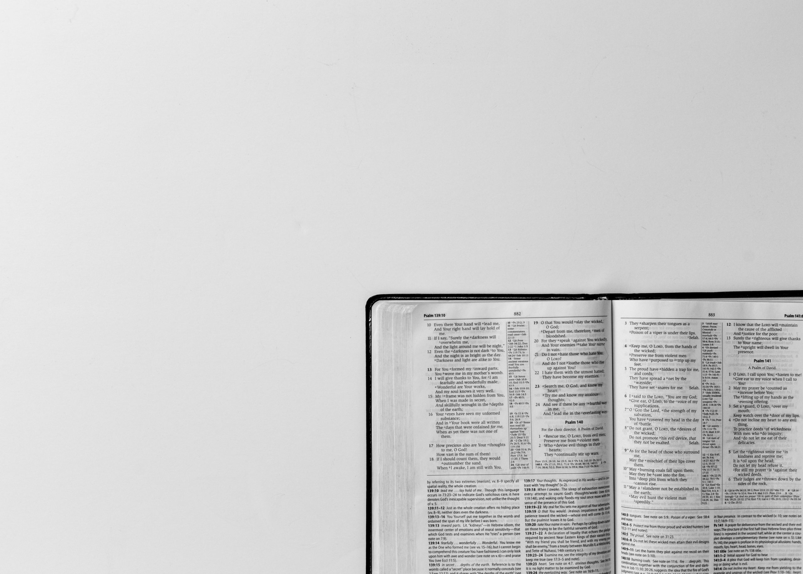 A Bible lies open in the corner of a white background.