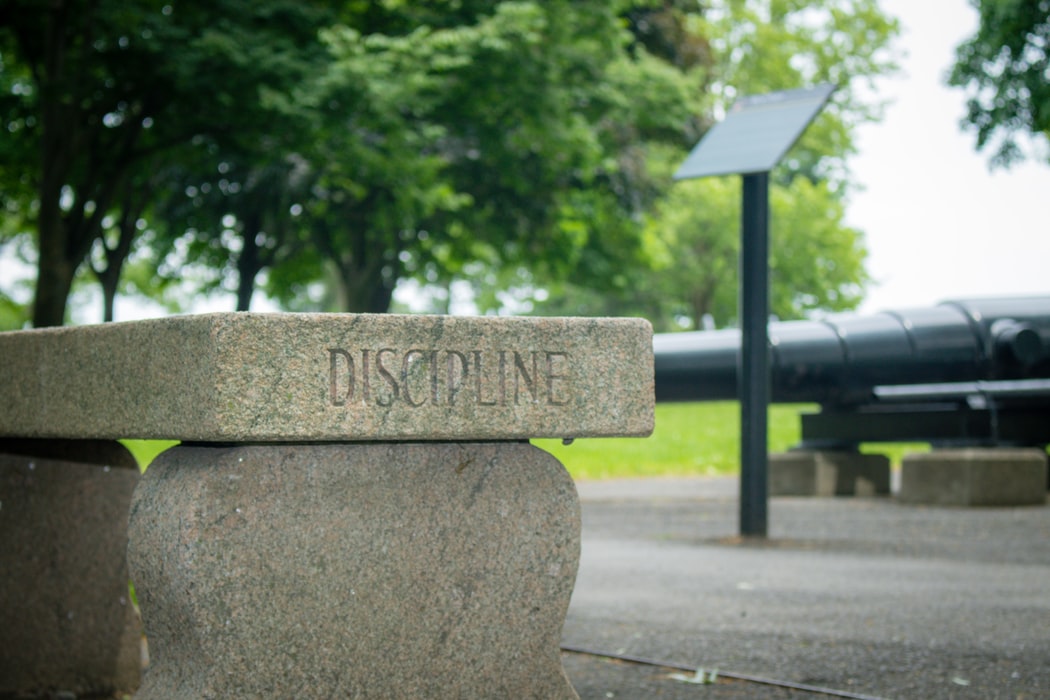 Um banco de pedra está gravado com a palavra disciplina.