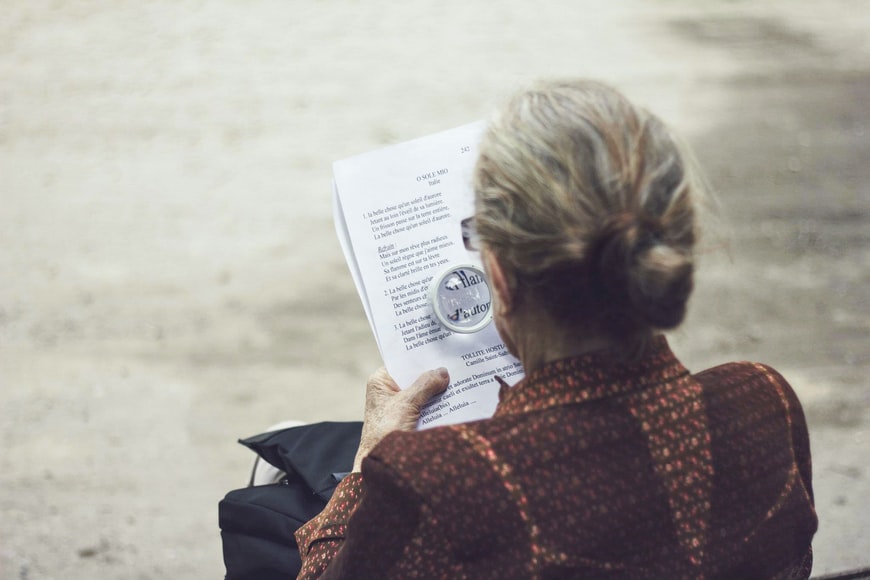 elderly woman reads with a magnifying glass