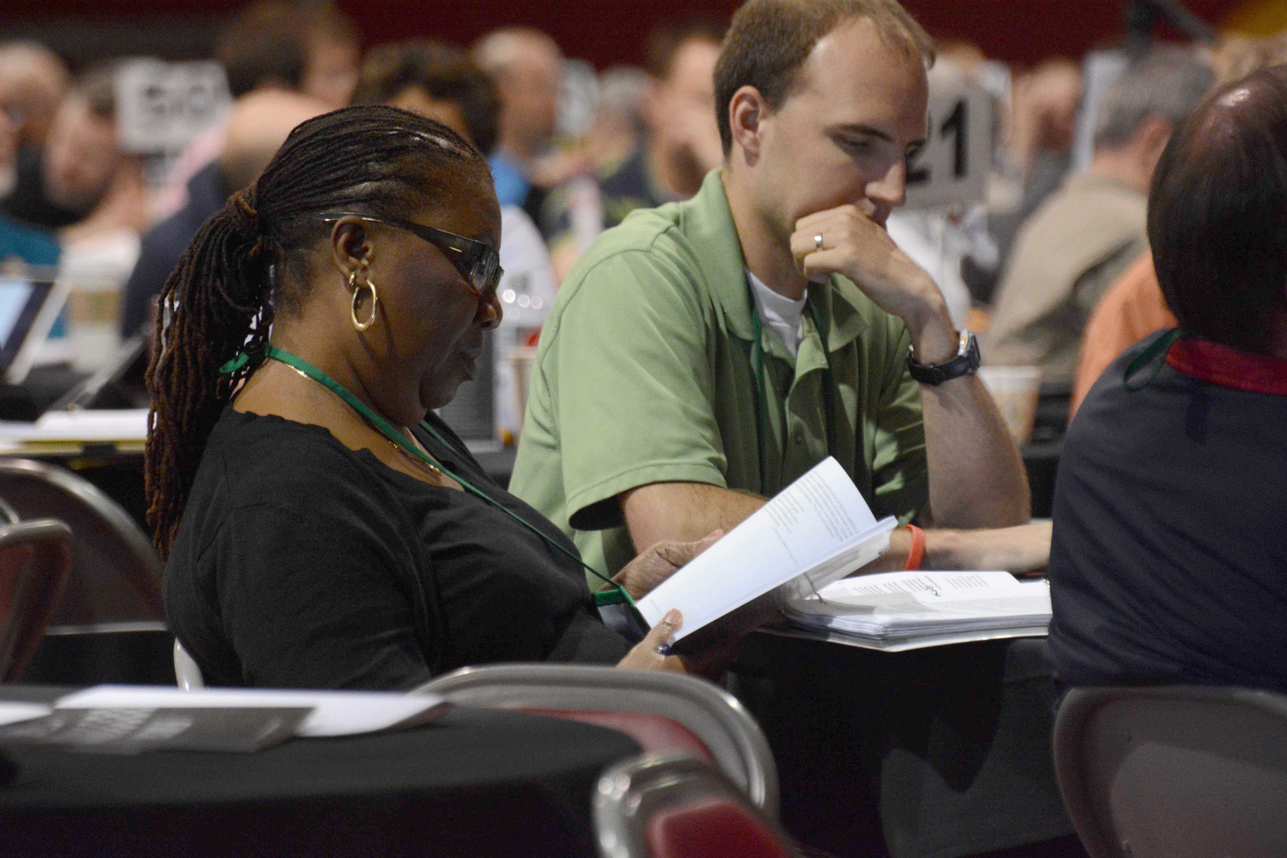 Two delegates reading the workbook at their plenary table at General Synod 2014