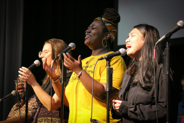 Three women lead worship with arms raised