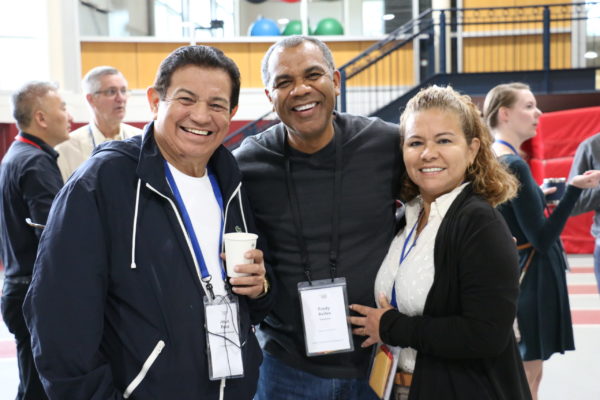 Three delegates standing together smiling during coffee time