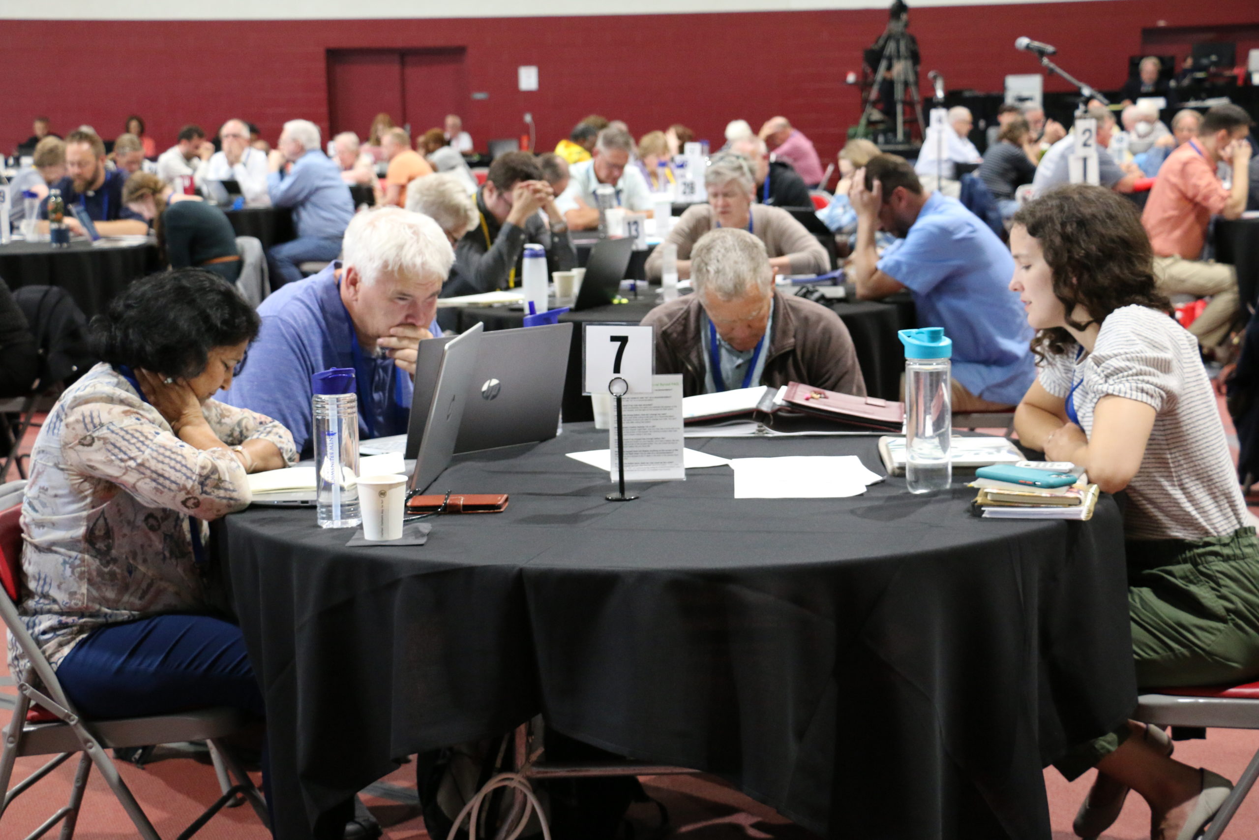 A table of delegates praying during synod