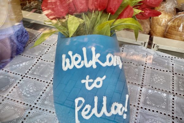 A blue wooden shoe filled with tulips with an inscription that says, "Welkom to Pella!"